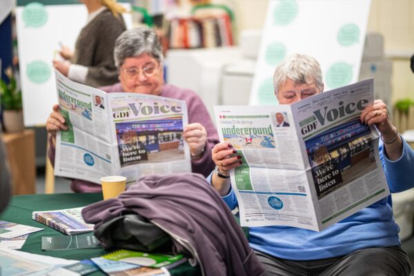 Two ladies sat together both reading a GDF Voice newspaper