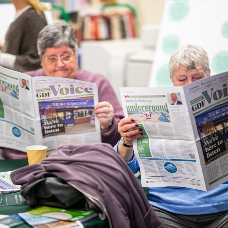 Two ladies sat together both reading a GDF Voice newspaper