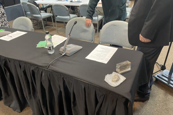 Image showing a table and chairs set up for a meeting with two people stood near the chairs.