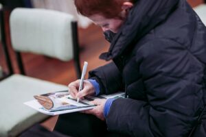 lady sat down and writing with a pen and filling out a feedback form