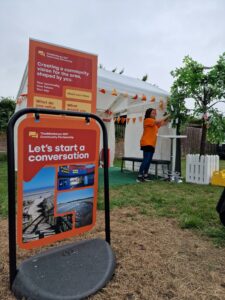 Engagement team display at an event. Gazebo in background and colourful banners in foreground