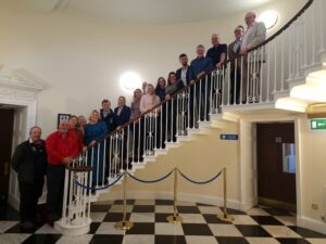 people stood in a group lining a staircase in a large hall