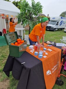 Display stand at an outdoor event. lady standing near a table and chatting to people.