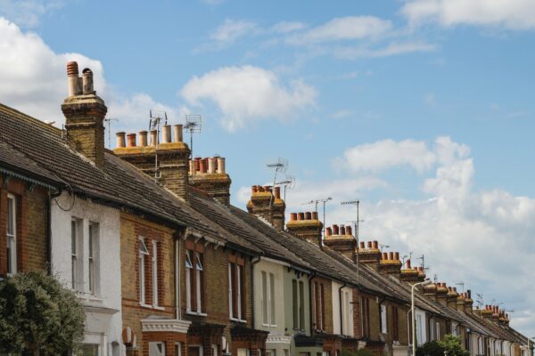 Image showing a row of houses and you can see the roof tops and chimneys and the blue sky above